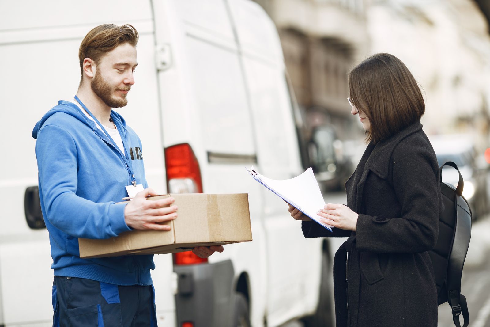 配送バンの脇で配達員が荷物を手渡している様子